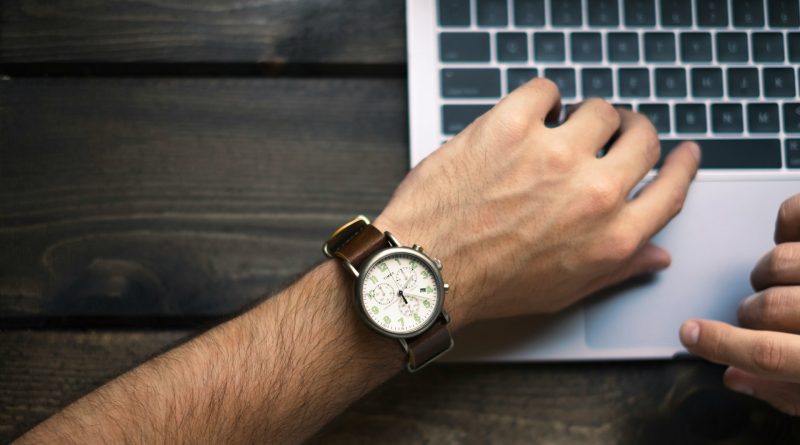 Eine Arm mit Uhr am Handgelenk auf einer Laptoptastatur
